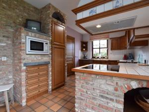 a kitchen with a brick fireplace and a microwave at Cozy Holiday Home in Noville with Private Terrace in Luzery