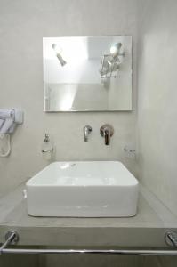 ein weißes Waschbecken im Bad mit Spiegel in der Unterkunft Pension Elena in Agia Anna