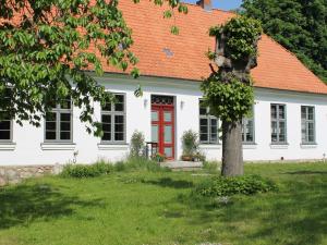 uma casa branca com um telhado laranja e uma porta vermelha em Lavish Apartment in Steffenshagen with Terrace em Steffenshagen