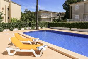 a pair of lounge chairs next to a swimming pool at Bellamar Apartments in Port d'Alcudia