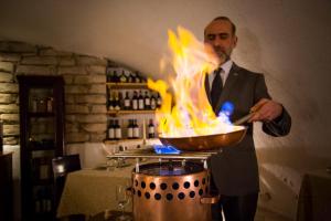 a man in a suit cooking in a pan with flames at Villa Nicolli Romantic Spa Resort - Adults Only in Riva del Garda