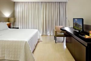 a hotel room with a bed, desk and television at Sia Park Executive Hotel in Brasília