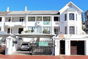 un edificio blanco con un paraguas delante en The Greenhouse Guesthouse, en Ciudad del Cabo