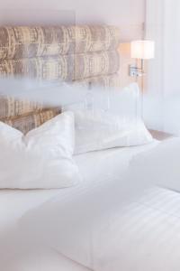 ein Schlafzimmer mit einem weißen Bett mit Kissen in der Unterkunft Hotel am Marktplatz - Landgasthof Wratschko - Gamlitz in Gamlitz