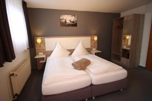 1 dormitorio con 1 cama blanca grande con almohadas blancas en Hotel Restaurant Jägerhof en Brunswick