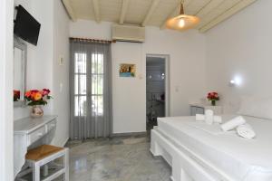 a white bedroom with a large bed and a television at Surfing Beach Village Paros in Santa Maria