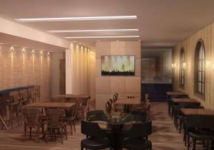 a restaurant with tables and chairs and a tv on the wall at Hotel Bernal in Ituiutaba