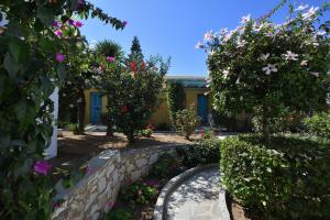 a garden with flowers and trees and a building at Surfing Beach Village Paros in Santa Maria