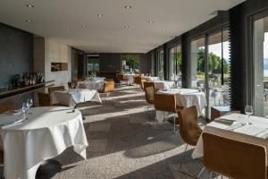 um restaurante com mesas e cadeiras brancas e janelas em Atmospheres em Le Bourget-du-Lac