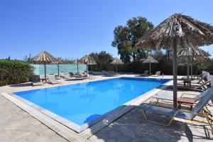 a swimming pool with chairs and umbrellas at Surfing Beach Village Paros in Santa Maria