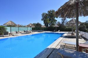 a swimming pool with chairs and umbrellas at Surfing Beach Village Paros in Santa Maria