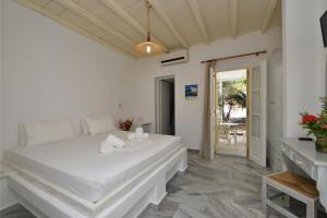 a bedroom with a large white bed and a table at Surfing Beach Village Paros in Santa Maria