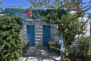 a pergola with blue doors and pink flowers at Surfing Beach Village Paros in Santa Maria