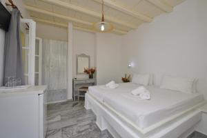a white bedroom with a large bed and a sink at Surfing Beach Village Paros in Santa Maria