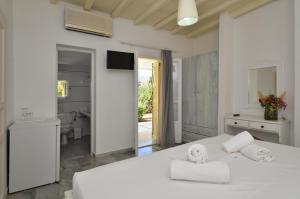a white bedroom with a white bed and a bathroom at Surfing Beach Village Paros in Santa Maria