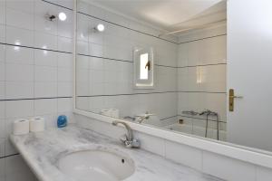 a white bathroom with a sink and a tub at Surfing Beach Village Paros in Santa Maria
