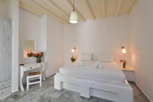 a white bedroom with a white bed and a mirror at Surfing Beach Village Paros in Santa Maria