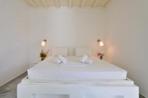 a white bedroom with a white bed with two pillows at Surfing Beach Village Paros in Santa Maria