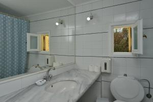 a bathroom with a sink and a toilet and a mirror at Surfing Beach Village Paros in Santa Maria
