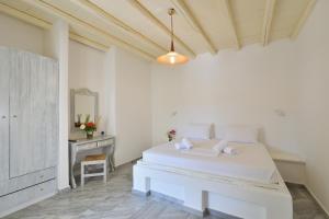 a white bedroom with a white bed and a table at Surfing Beach Village Paros in Santa Maria