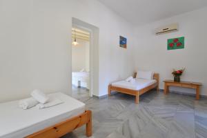 a white room with two beds and a table at Surfing Beach Village Paros in Santa Maria