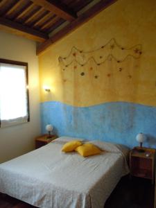 1 dormitorio con 1 cama con 2 almohadas amarillas en Il Farfasole, en Vigonovo
