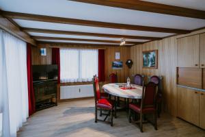 uma sala de jantar com uma mesa e cadeiras e uma televisão em Chalet Aloa em Adelboden