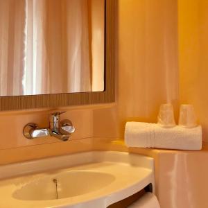 uma casa de banho com lavatório, espelho e toalhas em Premiere Classe Perpignan Sud em Perpignan