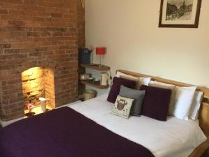 a bedroom with a bed with a brick fireplace at The Huntsman in Cheadle