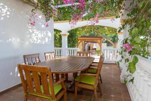 einen Holztisch und Stühle auf einer Terrasse mit Blumen in der Unterkunft Casa Atalaya en Villa de Nijar con piscina in Níjar