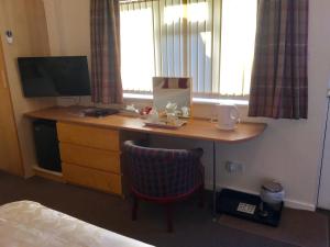 einen Schreibtisch in einem Hotelzimmer mit einem TV und einem Bett in der Unterkunft Ashleigh Lodge in Hunstanton