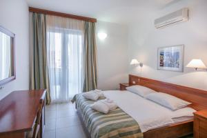 a bedroom with a bed and a desk and a window at Apartments Punta in Veli Lošinj