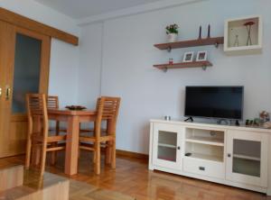 sala de estar con TV, mesa y sillas en COMSEREX-ASTURIAS, en Castropol