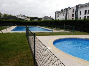 two swimming pools in a yard next to a fence at COMSEREX-ASTURIAS in Castropol
