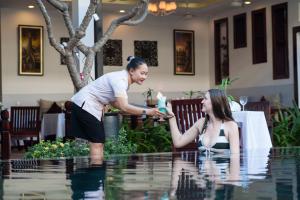 a woman is standing next to a woman in the pool at The Moon Residence & Spa in Siem Reap