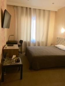 a hotel room with a bed and a table and a television at Hotel POSHALE in Bryansk