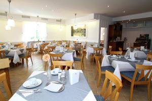 un restaurante lleno de mesas y sillas con manteles blancos en Hotel Lindemann, en Bad Nauheim