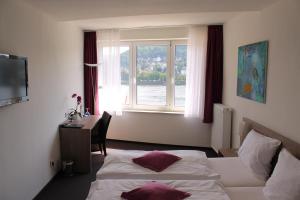 a hotel room with two beds and a desk and a window at RheinHotel ARTE in Remagen