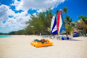 an orange kayak and a sailboat on a beach at Breezes Resort & Spa All Inclusive, Bahamas in Nassau
