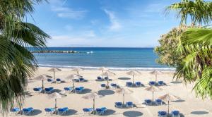 a beach with chairs and umbrellas and the ocean at All Senses Nautica Blue Exclusive Resort & Spa - All Inclusive in Fánai