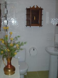 a bathroom with a toilet and a sink and a vase with flowers at Hotel Centras in Šakiai