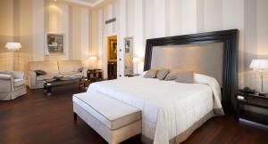 a bedroom with a large white bed and a living room at GH Palazzo Suite & SPA in Livorno