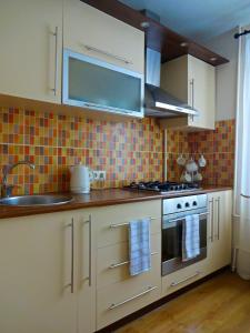 a kitchen with white cabinets and a stove top oven at Kaktuss Apartamenti in Valmiera