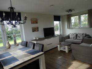 a living room with a dining table and a television at Vakantiehuis het Neerland in Biggekerke
