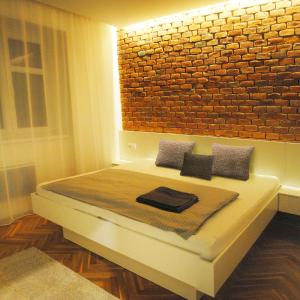 a bedroom with a bed with a brick wall at Apartments Centre in Style in Olomouc