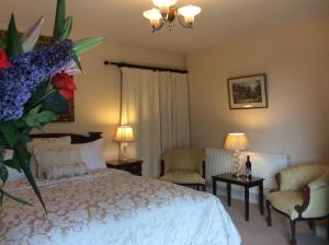 a bedroom with a bed and two chairs at Bretton Cottage in Eyam