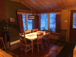 a dining room with a table and chairs and windows at Maison Bleue in Sainte-Anne-des-Monts