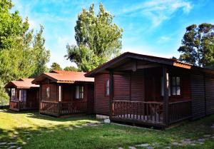 a couple of log cabins in a yard at Camping Preguntoiro in Sanxenxo