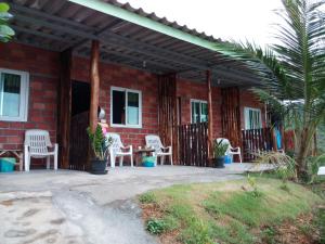 a patio with white chairs and a brick house at Cat Bungalow in Ko Lanta