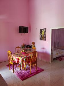 a dining room with a table and chairs and a pink wall at Gîtes Soussoune in Anse-Bertrand
